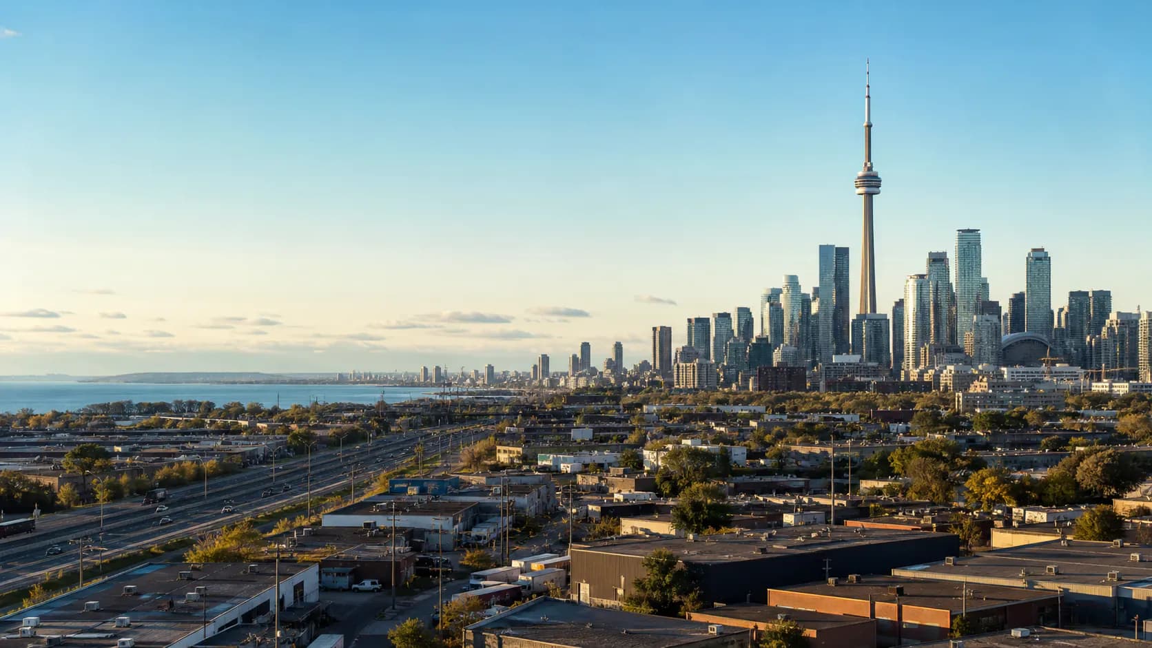 Editorial landscape representing Toronto, Ontario with the downtown skyline, CN Tower, Lake Ontario, and industrial foreground